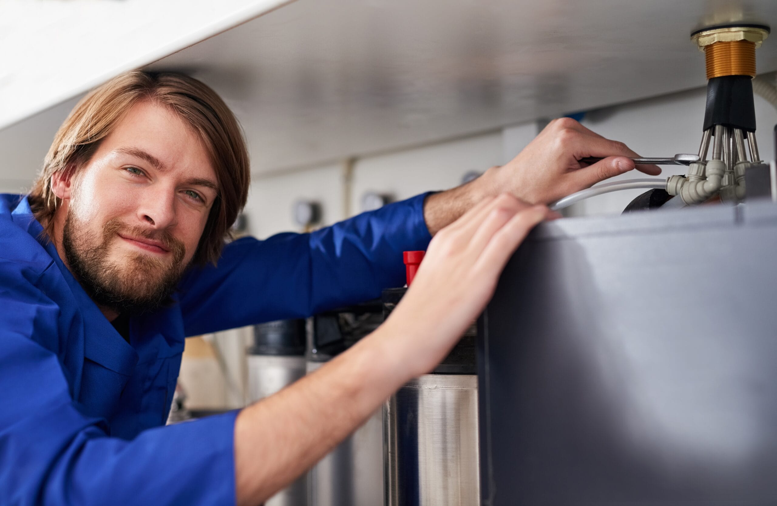 Technician servicing a residential water heater tank in Duarte